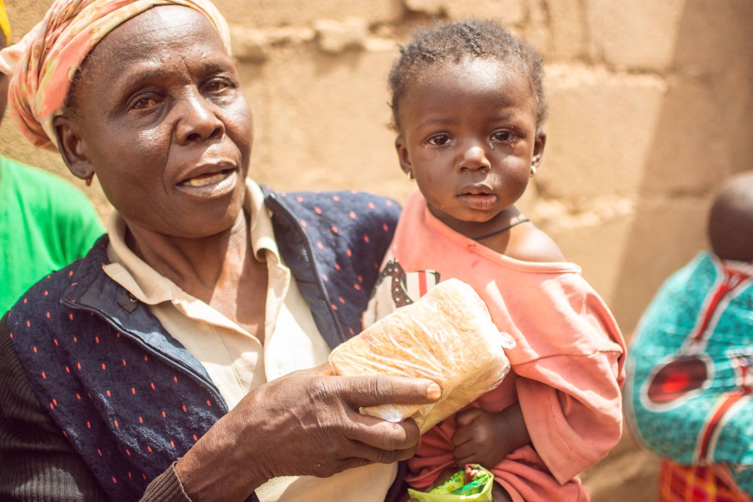 Woman holding child with a loaf of bread.